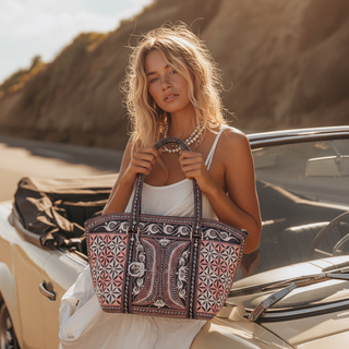 Woman holding a patterned bag by a car on a beach