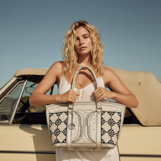 Woman holding a patterned handbag in front of a vintage car