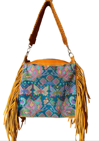 Colorful handbag with fringes hanging on a wooden door