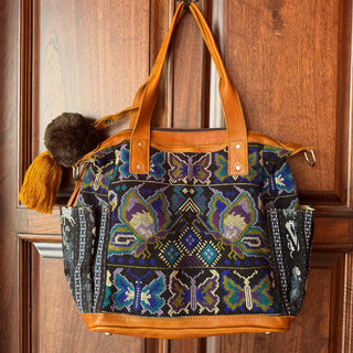 Decorative handbag with butterfly pattern hanging on a wooden door