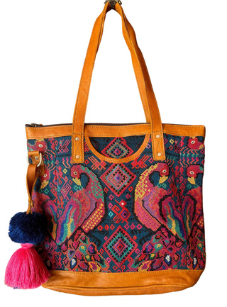 Colorful embroidered handbag with parrot design hanging on a wooden door