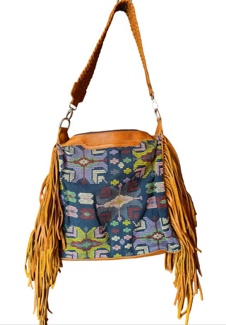 Handbag with fringe details on a wooden door