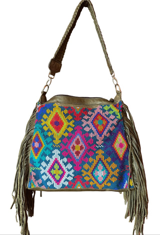 Colorful handbag with geometric pattern and fringes hanging on a wooden door