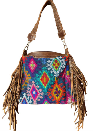 Colorful handbag with geometric pattern and fringes hanging on a wooden door