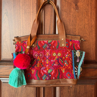 Colorful handbag with patterns and tassels on a wooden surface