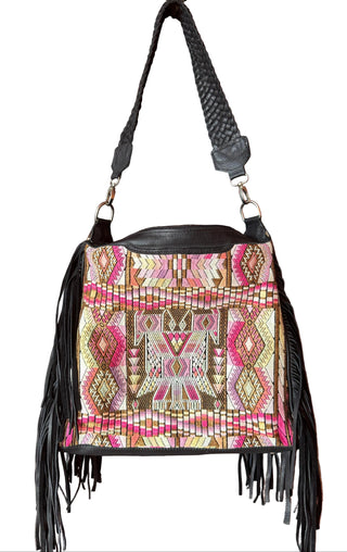 Handbag with tribal pattern and fringes hanging on a wooden door