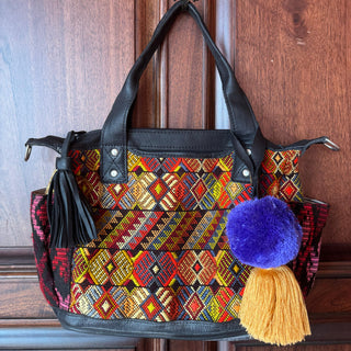 Colorful handbag with geometric pattern and tassels on a wooden door