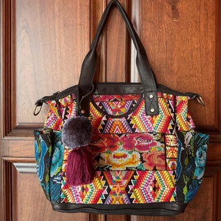 Colorful patterned handbag with tassels hanging on a wooden door