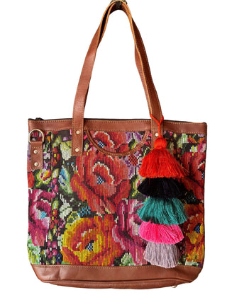 Colorful embroidered handbag with tassels hanging on a wooden door