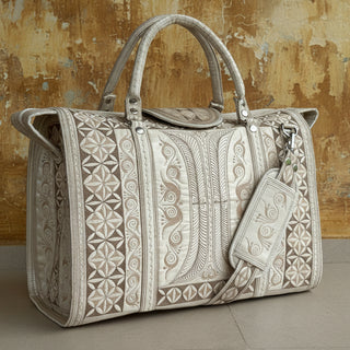 Beige patterned handbag on a light wooden floor with a white wall background