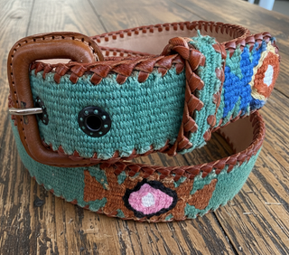 Colorful woven belt with brown leather accents on a wooden surface