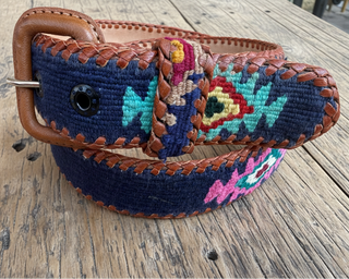 Colorful embroidered belt with brown leather buckle on a wooden surface