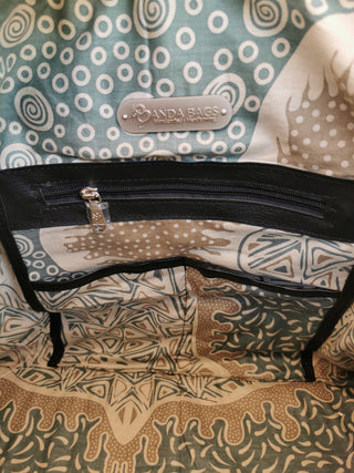 Close-up of a black bag with a visible brand label on a patterned fabric background