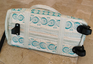 Patterned suitcase with wheels on a tiled floor