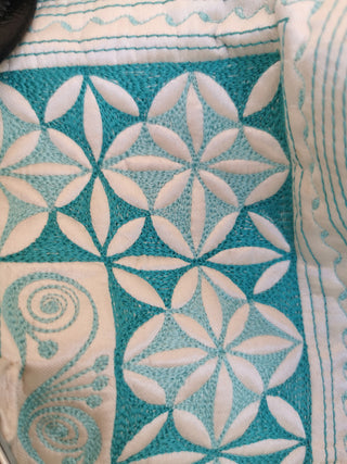 Close-up of a textured fabric with geometric pattern and shell design.