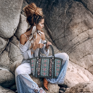 Woman sitting on rocks holding a patterned handbag