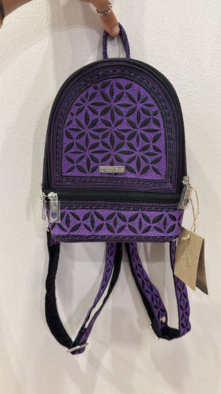 Purple geometric patterned backpack held by a person on a white background
