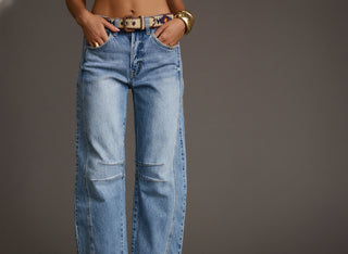 Person wearing blue jeans with a plain background