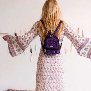Woman wearing a purple backpack with a white wall background